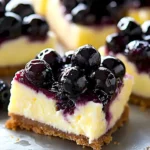 Zitronen-Käsekuchen-Riegel mit Blaubeertopping auf einem Teller.